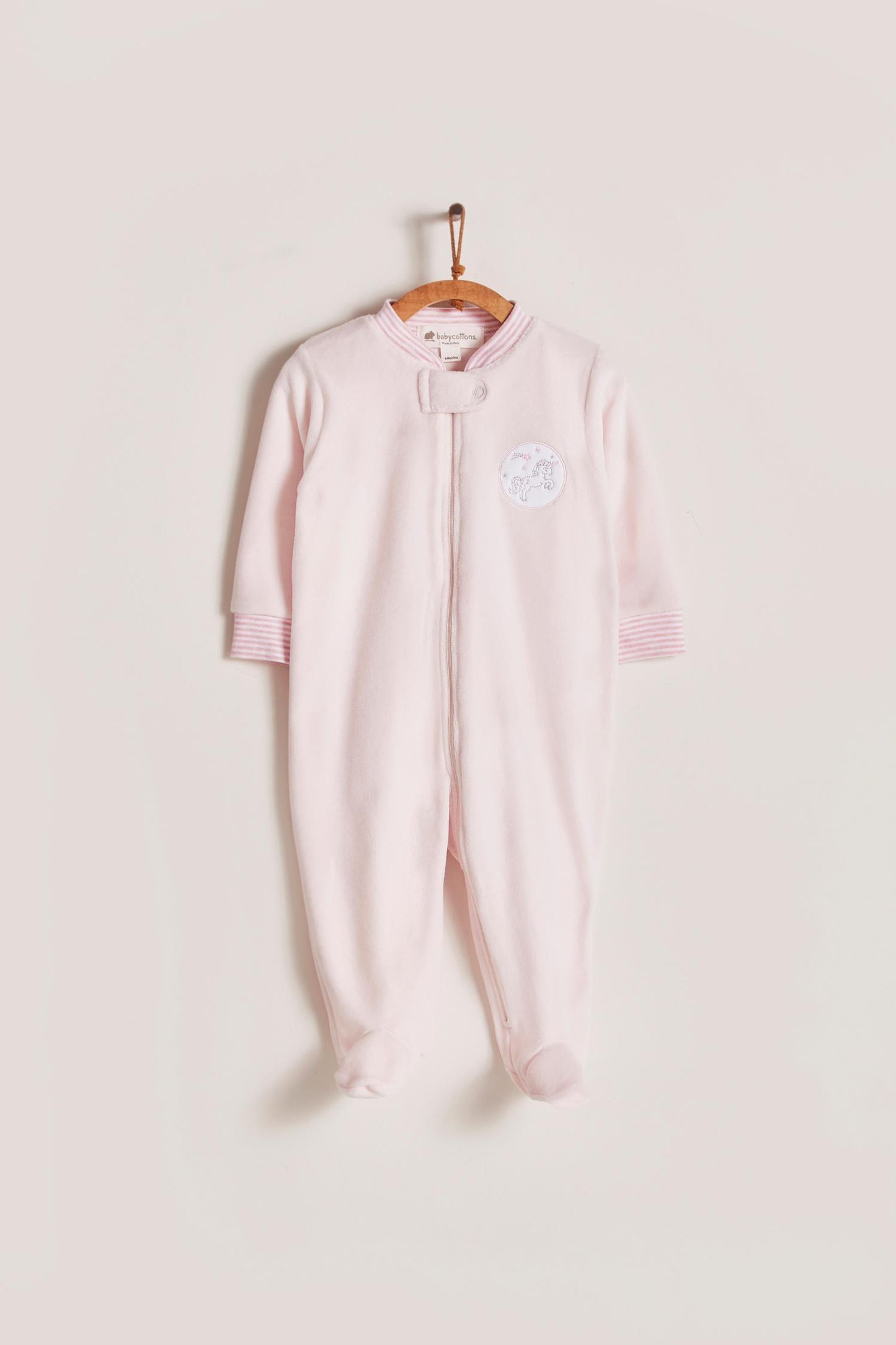 Super warm and soft plush pyjama, ideal to stay warm and comfortable during winter! With long-sleeves, footed and with front closure. Features a lovely striped ribbed collar and cuffs, alongside an embroidered patch on the front. Colour: Pink. Composition: 85% Peruvian Pima cotton, 15% polyester. Made in Peru. Machine washable. Safety warning: Keep away from fire.