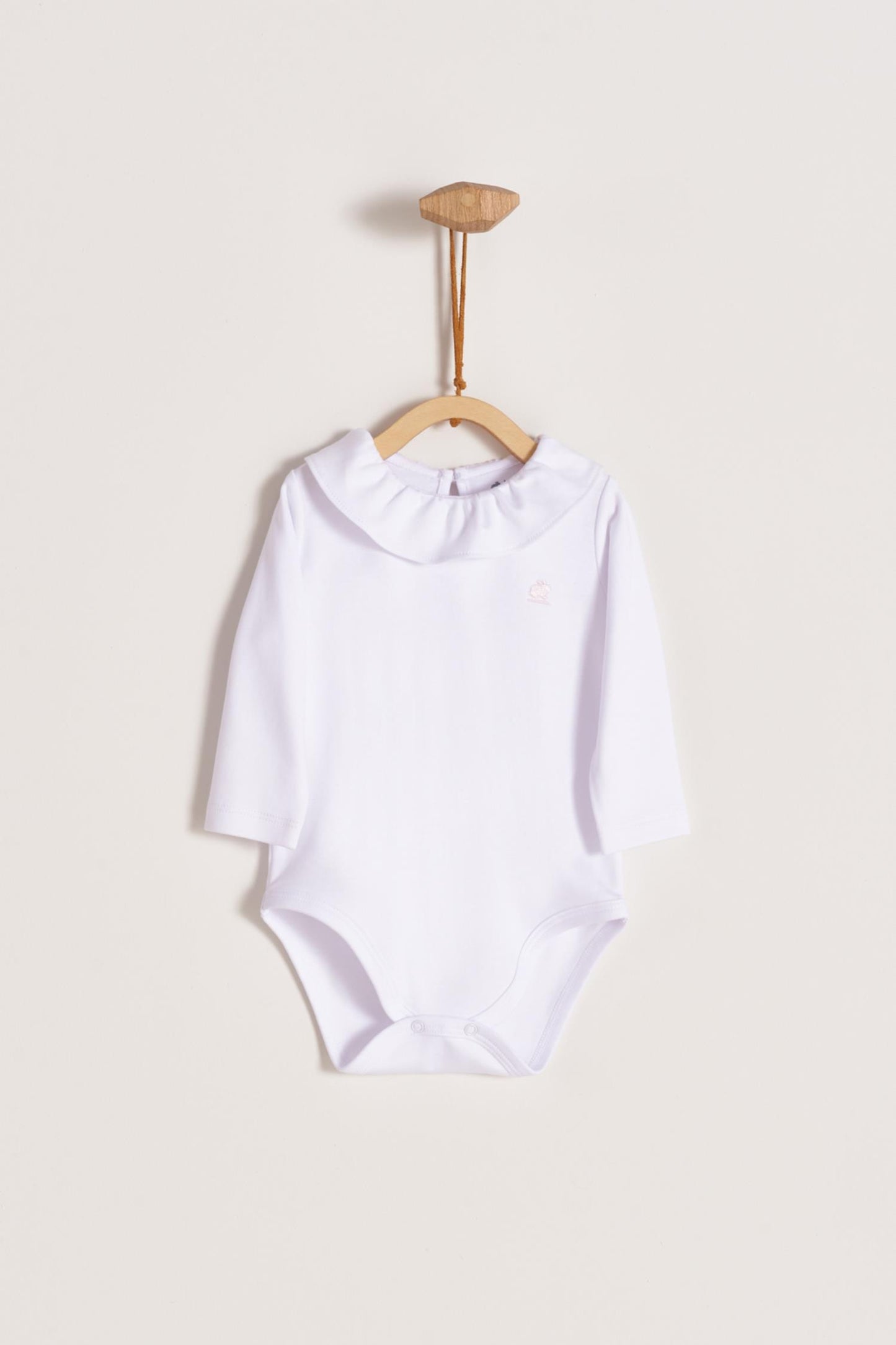 Made from 100% super soft Pima cotton. Long sleeves bodysuit, with cute ruffle collar around. A classic must have! Popper fastenings around the legs and the back make changing easy, too. Colour: White. Composition: 100% Peruvian Pima Cotton. Made in Peru. Machine washable.