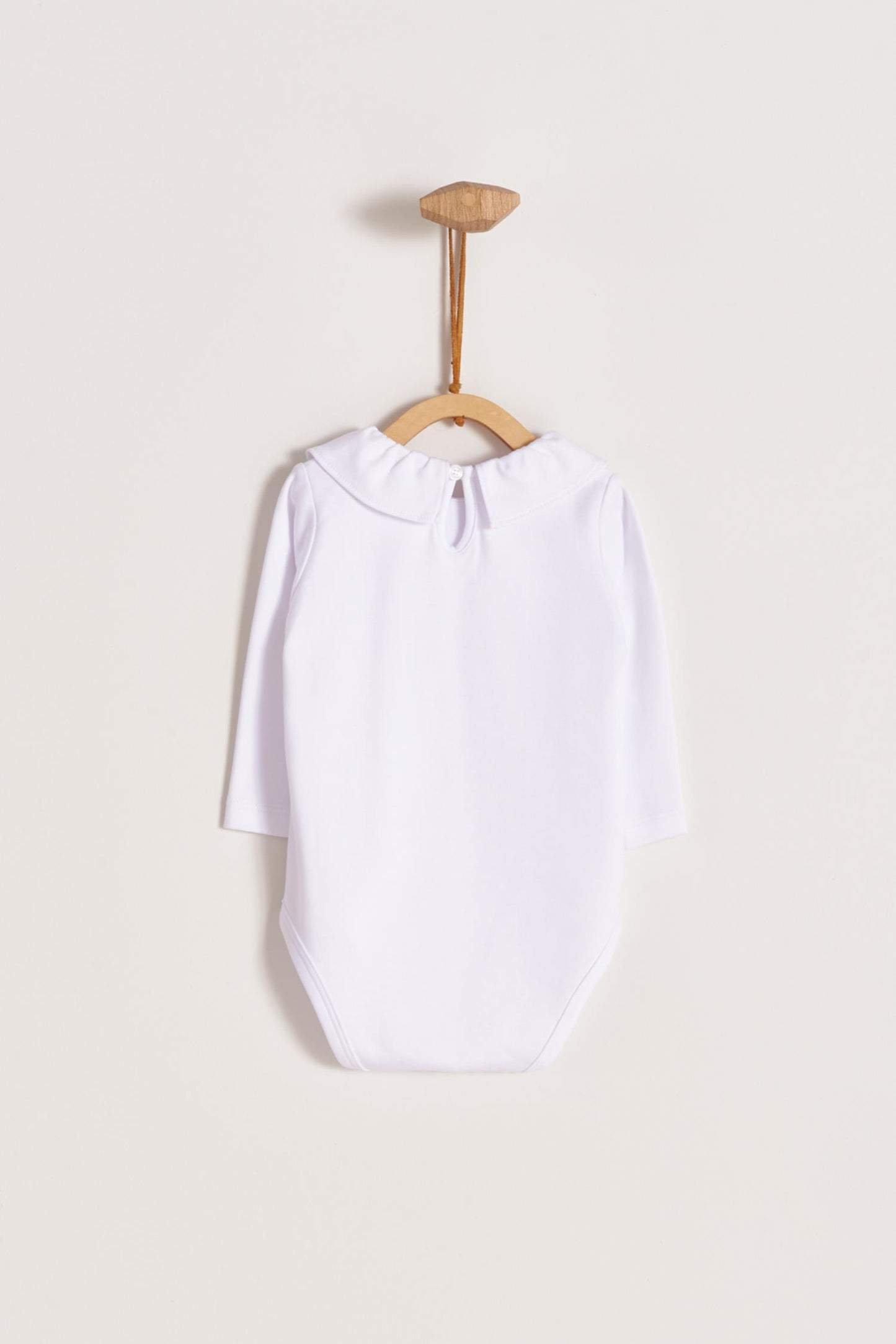 Made from 100% super soft Pima cotton. Long sleeves bodysuit, with cute ruffle collar around. A classic must have! Popper fastenings around the legs and the back make changing easy, too. Colour: White. Composition: 100% Peruvian Pima Cotton. Made in Peru. Machine washable.