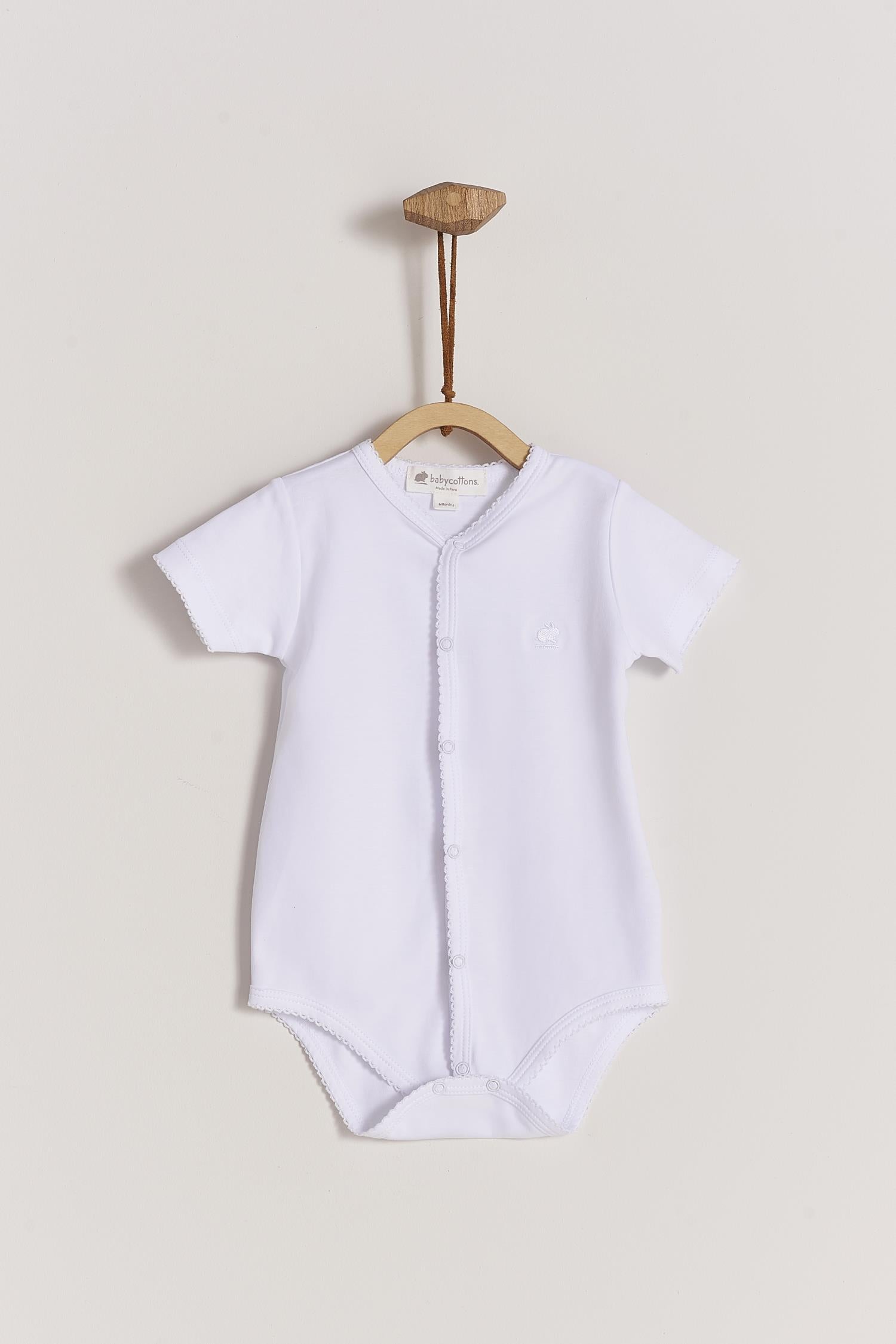 This baby basic short sleeve snapped bodysuit made with 100% super soft and resistant Pima cotton is a must have for your little one. Features a delicate embroidered neckline and sleeves alongside our cute logo bunny embroidered at chest. A baby's wardrobe essential! Popper fastenings around the legs and the front make changing easy, too. Colour: White. Composition: 100% Peruvian Pima Cotton.  Made in Peru.  Machine washable.
