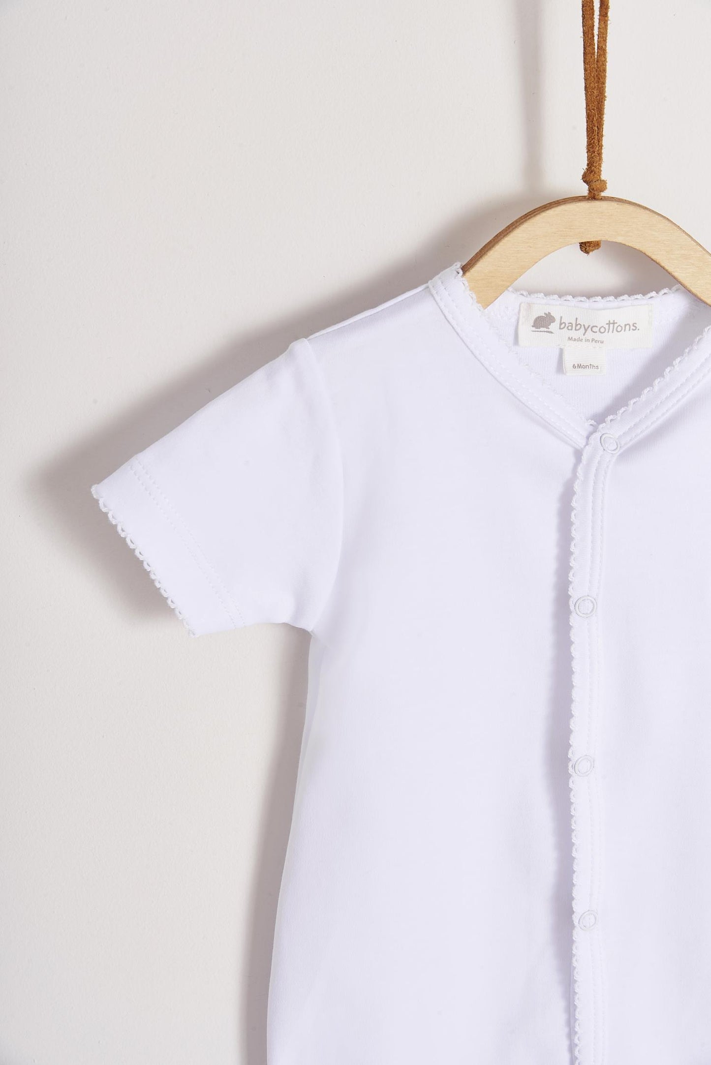 This baby basic short sleeve snapped bodysuit made with 100% super soft and resistant Pima cotton is a must have for your little one. Features a delicate embroidered neckline and sleeves alongside our cute logo bunny embroidered at chest. A baby's wardrobe essential! Popper fastenings around the legs and the front make changing easy, too. Colour: White. Composition: 100% Peruvian Pima Cotton.  Made in Peru.  Machine washable.