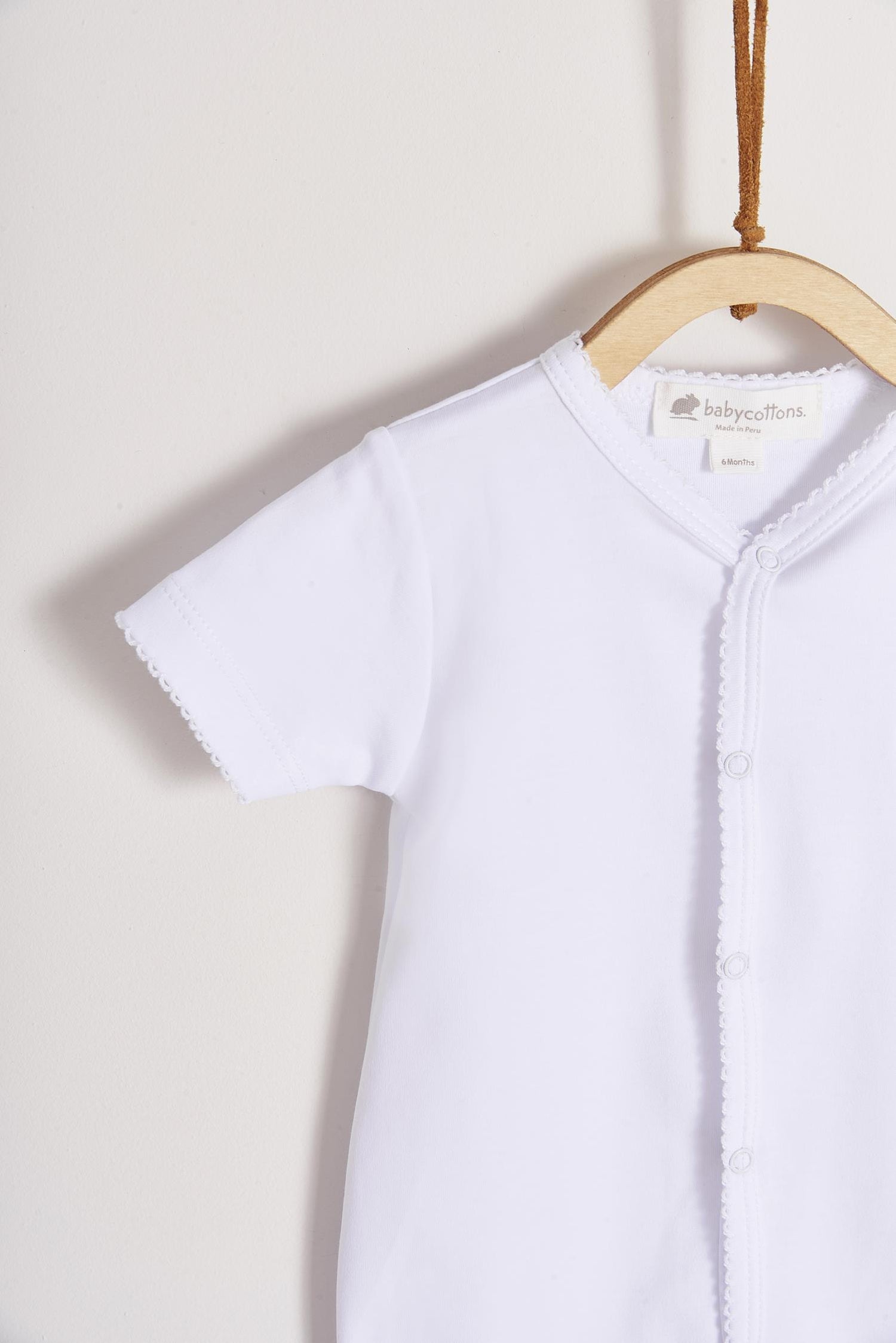 This baby basic short sleeve snapped bodysuit made with 100% super soft and resistant Pima cotton is a must have for your little one. Features a delicate embroidered neckline and sleeves alongside our cute logo bunny embroidered at chest. A baby's wardrobe essential! Popper fastenings around the legs and the front make changing easy, too. Colour: White. Composition: 100% Peruvian Pima Cotton.  Made in Peru.  Machine washable.