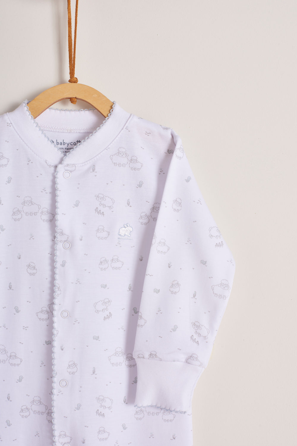 This super soft 100% Pima cotton, long-sleeve, footed pyjama with full snap closure is a maternity must-have! The pyjama has delicate picot edging and it features our lovely Fluffy Sheep print!  In size NB, the cuffs give the option of making them mittens for the baby's first days, and can then be folded again. Colour: White with pink. Composition: 100% Peruvian Pima Cotton.  Made in Peru. Machine washable. Safety warning: Keep away from fire.