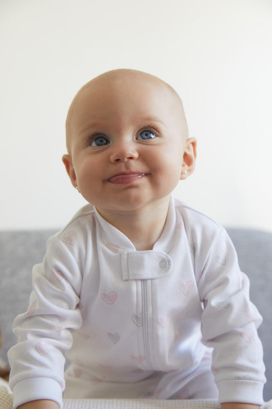 Hearts is classic, cute and perfect for naptime!  Your little one can grow with it and wear it for a longest time. With zipper added for more comfort and practicality. Starting in 12 months all our footies are snug fit. Colour: White with pink and grey details. Composition: 100% Peruvian Pima Cotton.  Made in Peru. Machine washable. Safety warning: Keep away from fire.