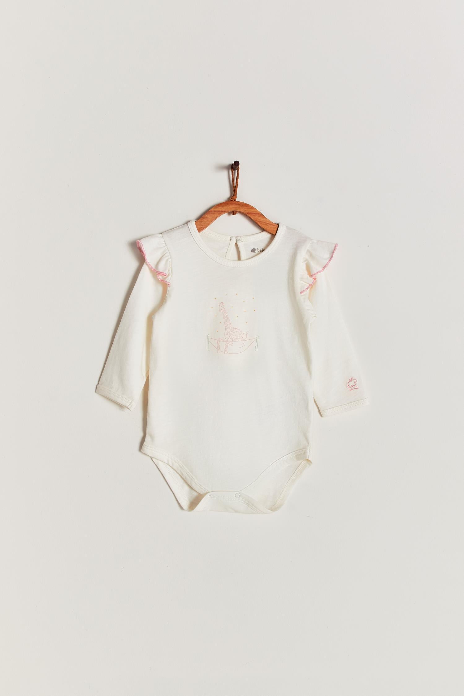 Made from 100% super soft Pima cotton. Cute long sleeve bodysuit with ruffler in shoulders, our Safari bodysuit features a beautiful giraffe balancing on bed. Popper fastenings around the legs make changing easy, too. Colour: Taupe with pink. Composition: 100% Peruvian Pima Cotton.  Made in Peru.  Machine washable.