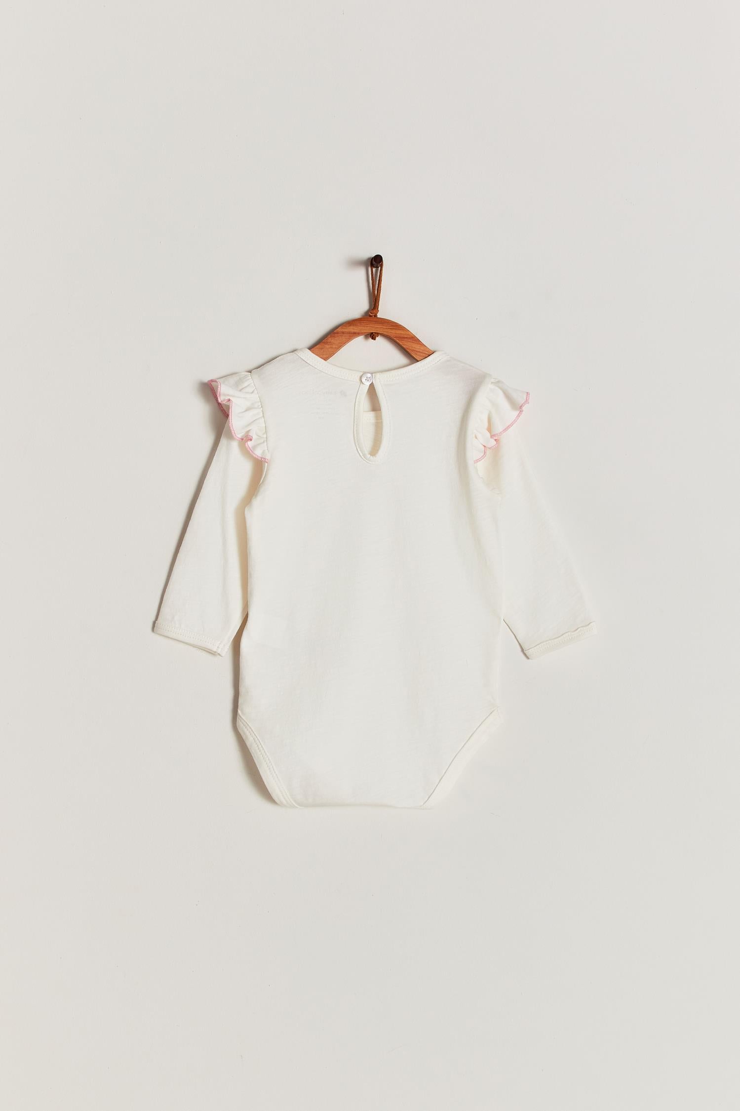 Made from 100% super soft Pima cotton. Cute long sleeve bodysuit with ruffler in shoulders, our Safari bodysuit features a beautiful giraffe balancing on bed. Popper fastenings around the legs make changing easy, too. Colour: Taupe with pink. Composition: 100% Peruvian Pima Cotton.  Made in Peru.  Machine washable.