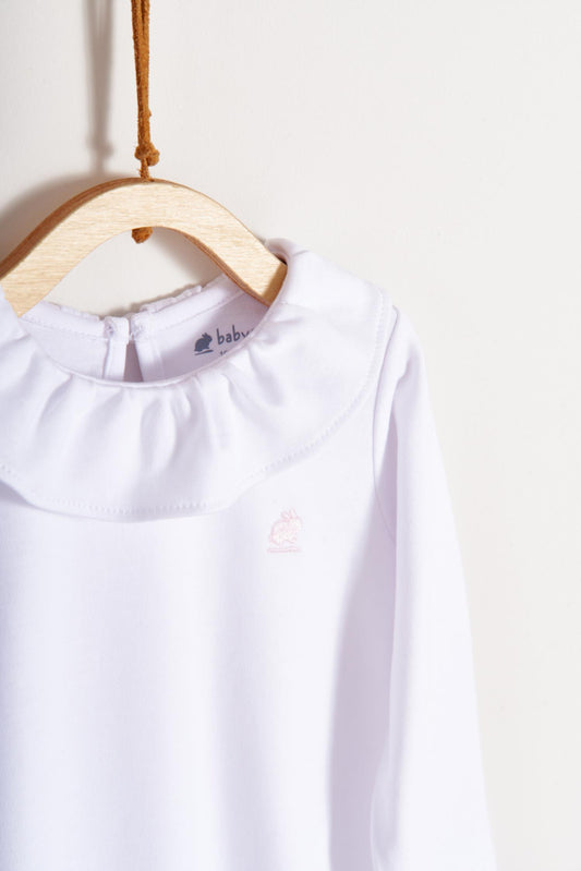 Made from 100% super soft Pima cotton. Long sleeves bodysuit, with cute ruffle collar around.  A classic must have! Popper fastenings around the legs and the back make changing easy, too. Colour: White. Composition: 100% Peruvian Pima Cotton.  Made in Peru.  Machine washable. 