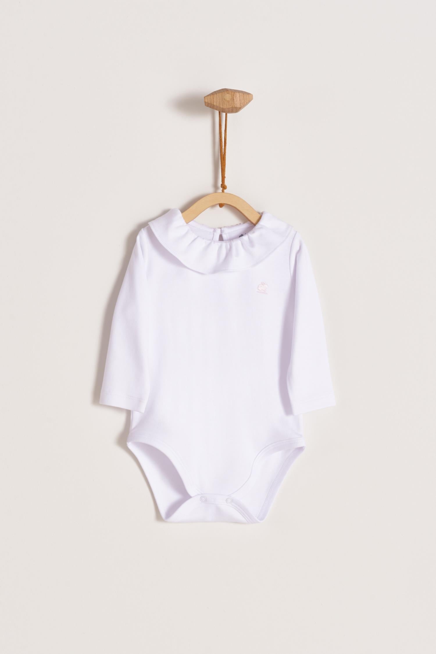 Made from 100% super soft Pima cotton. Long sleeves bodysuit, with cute ruffle collar around.  A classic must have! Popper fastenings around the legs and the back make changing easy, too. Colour: White. Composition: 100% Peruvian Pima Cotton.  Made in Peru.  Machine washable. 