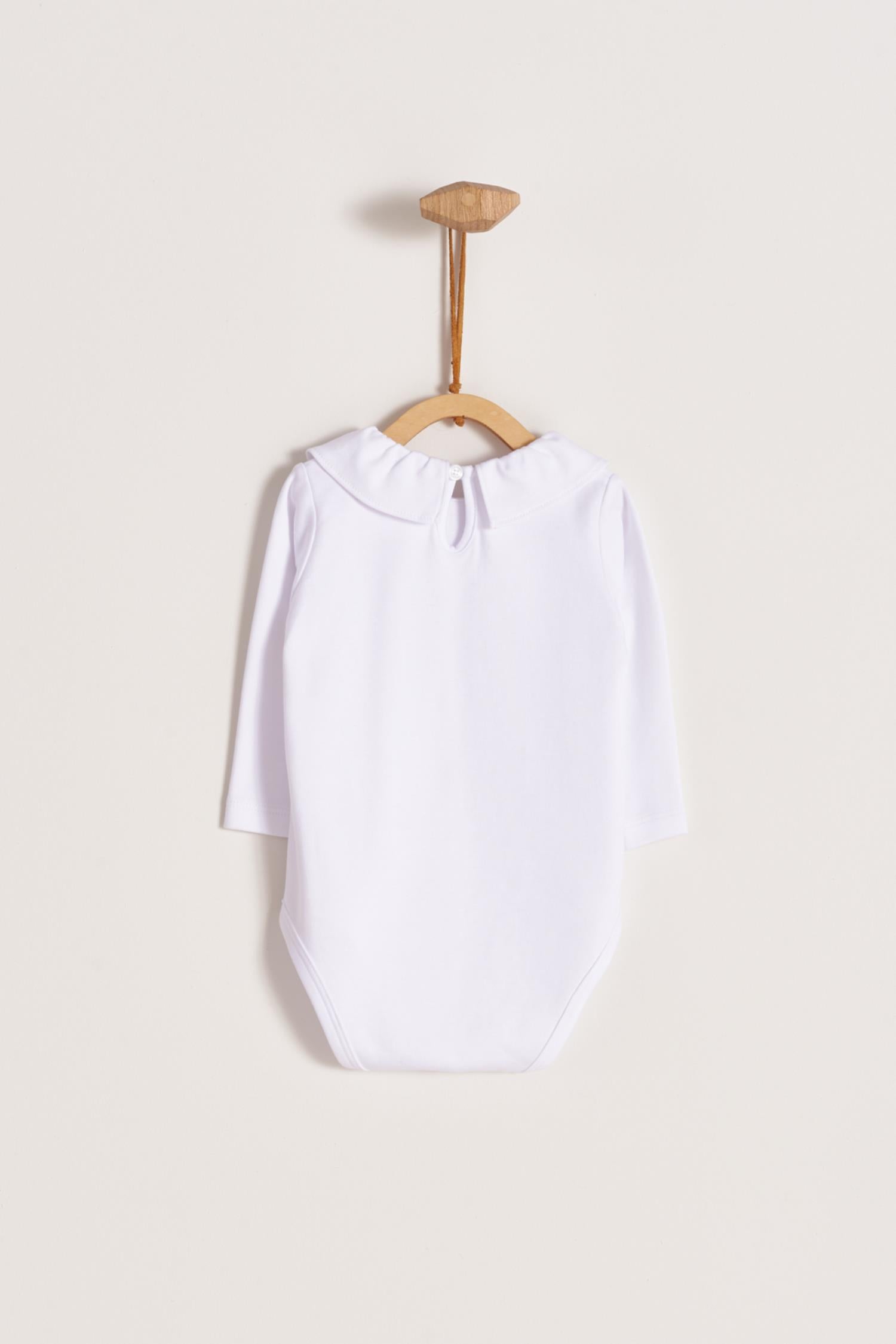 Made from 100% super soft Pima cotton. Long sleeves bodysuit, with cute ruffle collar around.  A classic must have! Popper fastenings around the legs and the back make changing easy, too. Colour: White. Composition: 100% Peruvian Pima Cotton.  Made in Peru.  Machine washable. 