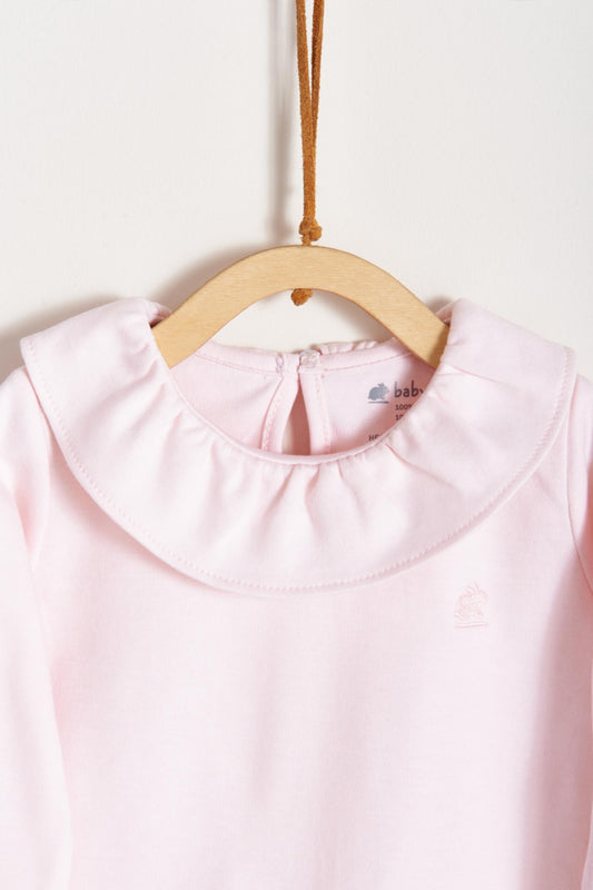Made from 100% super soft Pima cotton. Long sleeves bodysuit, with cute ruffle collar around.  A classic must have! Popper fastenings around the legs and the back make changing easy, too. Colour: Pink. Composition: 100% Peruvian Pima Cotton.  Made in Peru.  Machine washable.