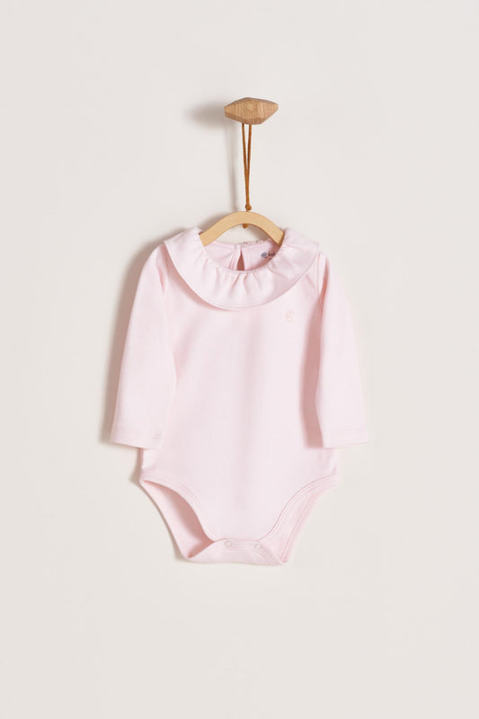 Made from 100% super soft Pima cotton. Long sleeves bodysuit, with cute ruffle collar around.  A classic must have! Popper fastenings around the legs and the back make changing easy, too. Colour: Pink. Composition: 100% Peruvian Pima Cotton.  Made in Peru.  Machine washable.