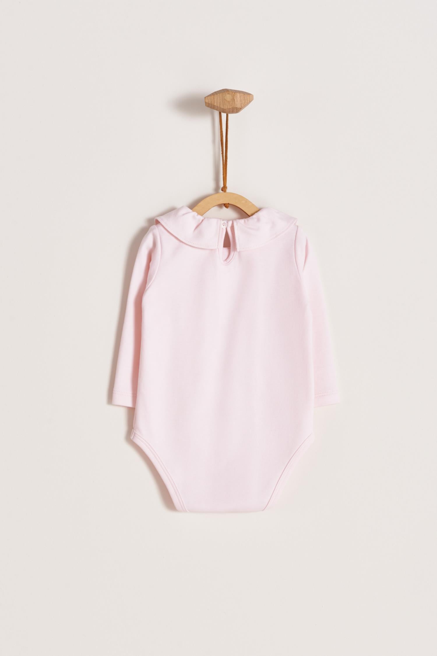 Made from 100% super soft Pima cotton. Long sleeves bodysuit, with cute ruffle collar around.  A classic must have! Popper fastenings around the legs and the back make changing easy, too. Colour: Pink. Composition: 100% Peruvian Pima Cotton.  Made in Peru.  Machine washable.