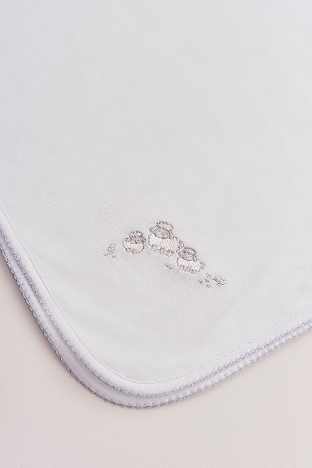 Crafted from super soft Pima cotton, this receiving blanket makes babies first months extra cozy. This two sided blanket features a sleek white finish with an embroidered Fluffy Sheep, while the other side comes with a full print of our lovely Fluffy Sheep collection. Approximate measurement: 100 cm x 100 cm. Composition: 100% Peruvian Pima Cotton.  Made in Peru.  Machine washable. 